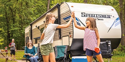 2020 KZ RV Sportsmen LE 332BHKLE Travel Trailer with family playing bean bags at campsite