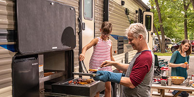 2020 KZ RV Sportsmen LE 332BHKLE Travel Trailer with family preparing dinner at outside grill