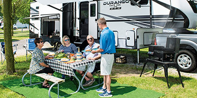 2023 KZ RV Durango Half Ton D256RKT Fifth Wheel Exterior Lifestyle Couples Cookout Vertical 2