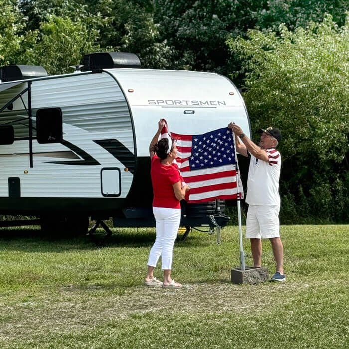 KZ RV Sportsmen SE Travel Trailer with Couple Hanging American Flag